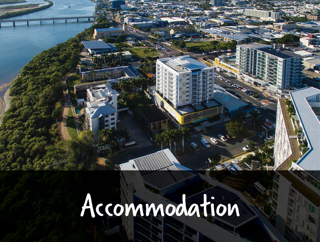 An aerial view of the city centre of Mackay with tall apartment buildings and a text overlay that reads Accommodation