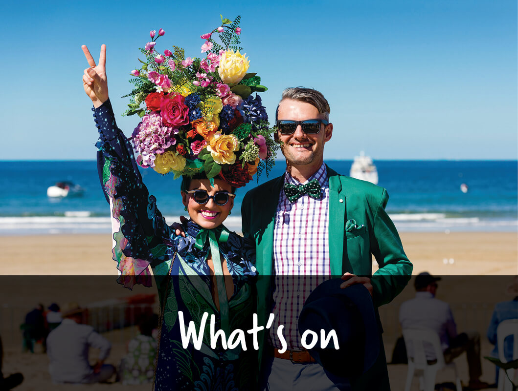 Two people dressed up for an event standing on a beach in Mackay with a text overlay that reads What's on