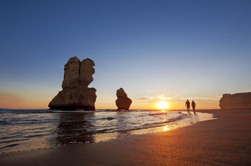 Couple hike past the Twelve Apostles at sunset